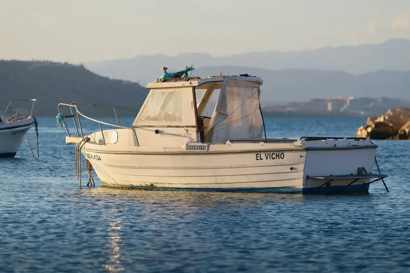 Una lancha a motor fondeada frente a la isla de Tabarca, en Santa Pola, al atardecer
