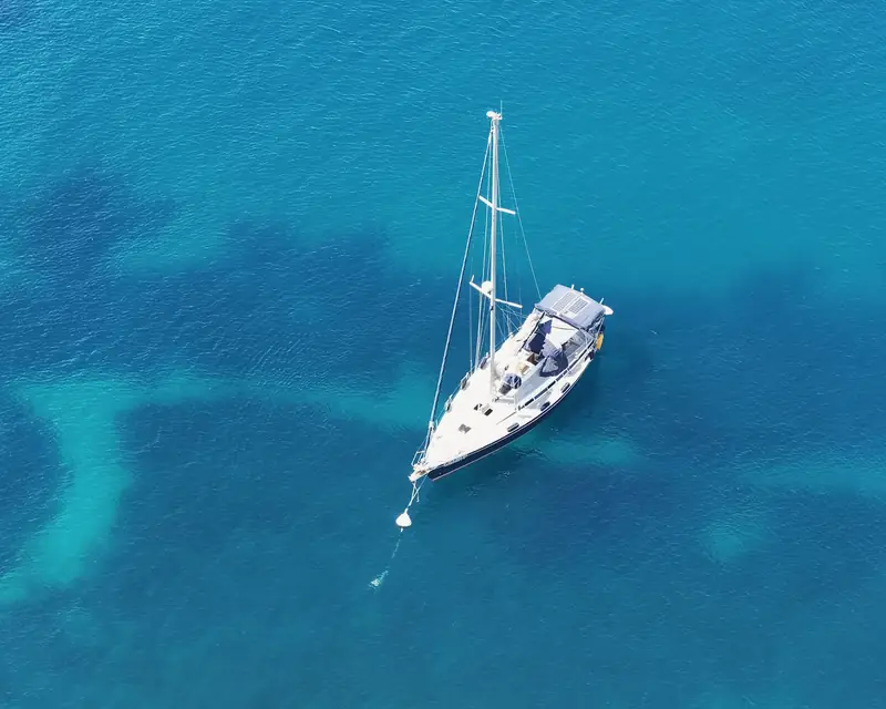 Un velero fondeado en agua clara frente a la costa de Alicante, visto desde arriba